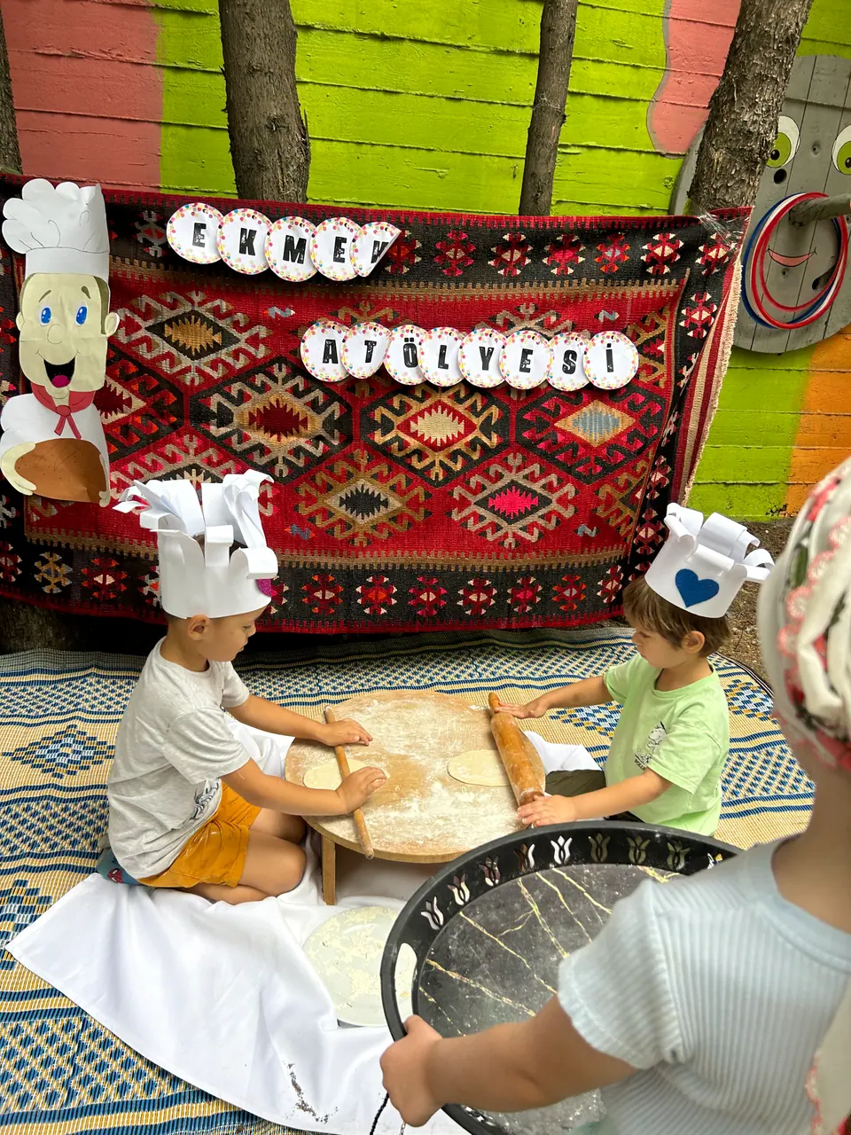 Aşçı şapkalı çocukların ahşap masada hamur açtığı ekmek atölyesi