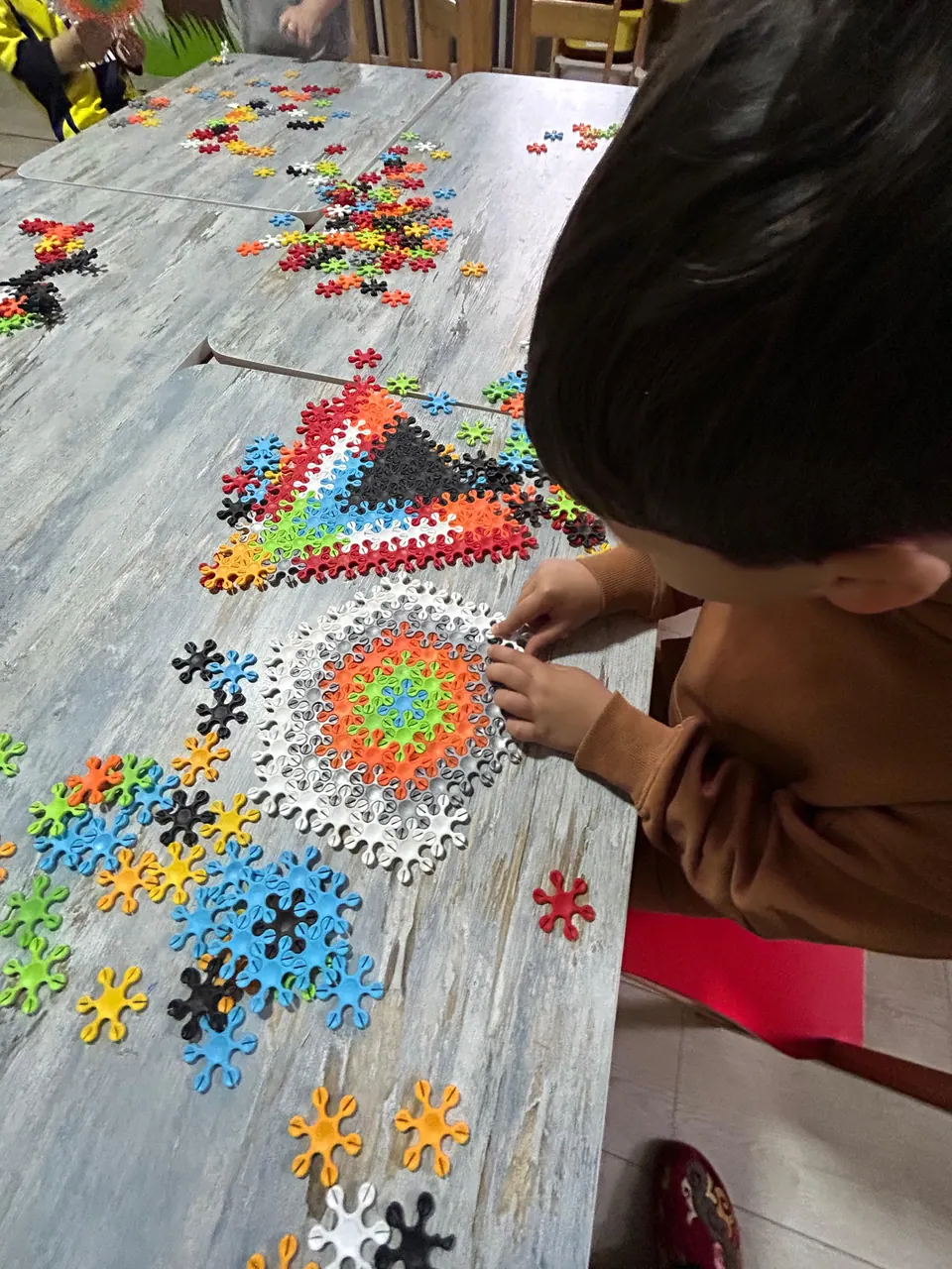 Çocuğun renkli parçalarla desen oluşturduğu sanat çalışması